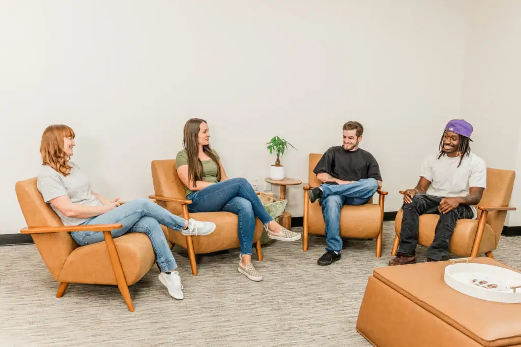 Group therapy session with diverse individuals in a counseling setting.