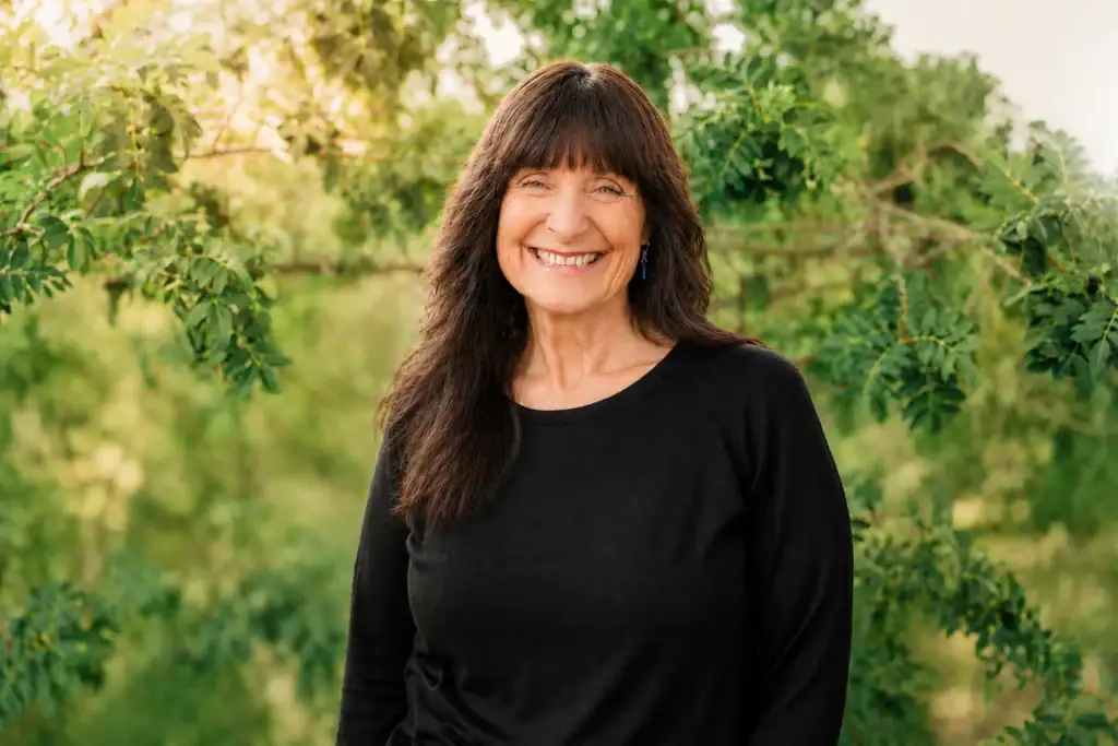 Woman smiling outdoors in natural setting, promoting mental health and wellness.