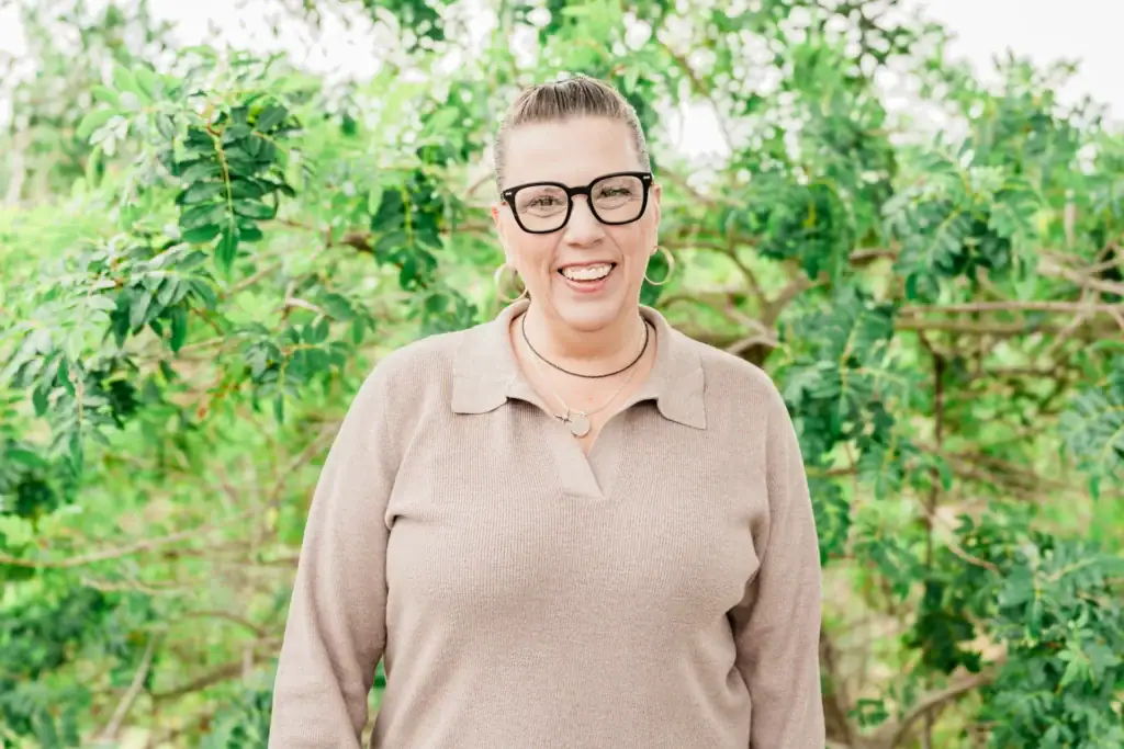 Woman smiling outdoors in a garden, promoting mental health and wellness.